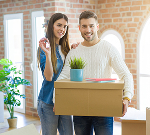 Young couple holding moving boxes in their new home.