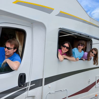 Family smiling while hanging out the windows of their RV.